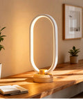 Modern Ellipse LED Desk Lamp With Wood Accent illuminating a wooden table, sleek aluminum edge visible, cozy vibes lighting
