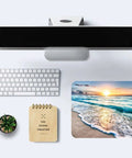 Overhead view of a Coastal Sunset Themed Mouse Pad For Laptop And Desktop Cute Customizable Small Desk Pad With Non Slip Rubber Base Ultra Smooth Surface Portable Office Accessory For Work From Home And Travel Dope Gift Idea next to a white keyboard, notebook, and small plant on a desktop.