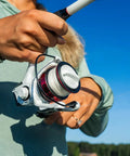 Person holding Max Pro Spinning Rod And Reel Combo 6 Foot 10 Inch, Size 2500 Reel, open in hands against a blue sky background.
