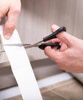 Indoor Outdoor Carpet Tape One Point Four One Inch By Forty Two Feet White Fiberglass Reinforced Durable Adhesive being cut for use