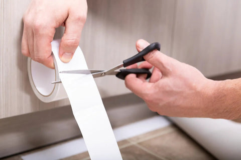 Indoor Outdoor Carpet Tape One Point Four One Inch By Forty Two Feet White Fiberglass Reinforced Durable Adhesive being cut for use