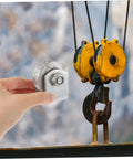 Industrial cast-iron V-groove pulley on mounting bracket held by hand; yellow hoist pulleys in background.