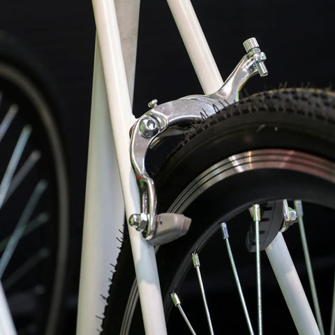 Close-up of All-In-One C Brake Caliper Set For Road, MTB, And BMX Bikes mounted on a rear wheel, showing metal construction.