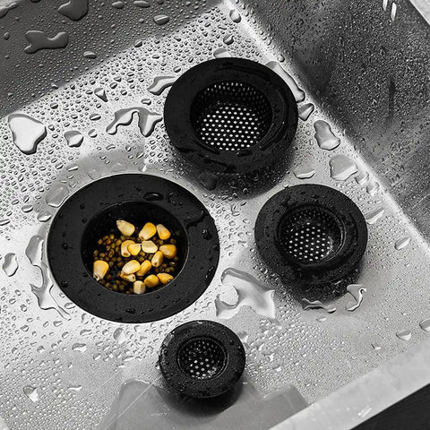 4 Pack Black 304 Stainless Steel Drain Stopper Hair Catcher And Shower Drain Cover For Bathtub Sink Strainer Clog Slayers in a wet sink with debris.