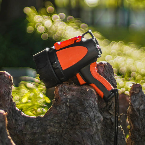 Rechargeable Waterproof Spotlight Up To 4500 Lumens Handheld Beast Mode Searchlight resting on tree stump in sunlight