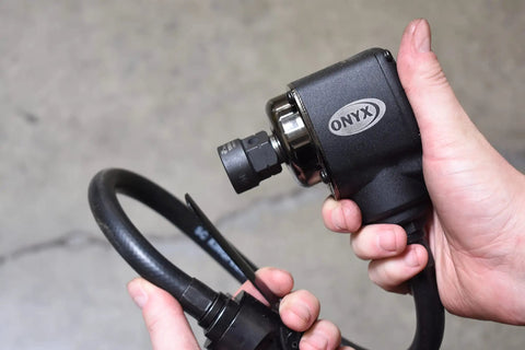 ONYX Half Inch Palm Impact Wrench With Remote Throttle, 445 Foot Pounds Torque, 25 Inch Swivel Hose held in hand