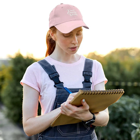 Woman wearing Omnia Vincit Pink Breathable Hat For Women With Adjustable Buckle Everyday Wear Cap outdoors writing in notebook