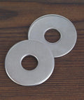 Two stainless steel flat washers on a wood surface; 1-inch outer diameter, 0.055-inch thick.