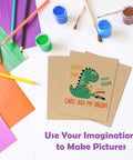 Craft table with colorful papers and 8.5x11 corrugated cardboard sheets featuring a dinosaur design for DIY crafts.