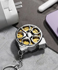 Hella Handy Keychain Tape Measure Boasting A Durable Steel Ruler Track And Totally Sick Wheel Hub Design For Pocket Ready Convenience When You Gotta Take Quick Measurements Right Now on a flat surface with electronic devices.