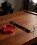 Rugged CNC Anodized Aluminum Telescope Dust Cover with red protective cap and strap on wooden table