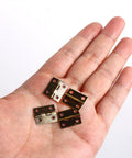Fifty Piece Mini Bronze Butt Hinges With Two Hundred Matching Screws Top Shelf Gear For Diy Crafts Jewelry Boxes Wooden Cases And Dollhouse Builds Heavy Duty Hardware That Truly Holds Tight held in a hand.