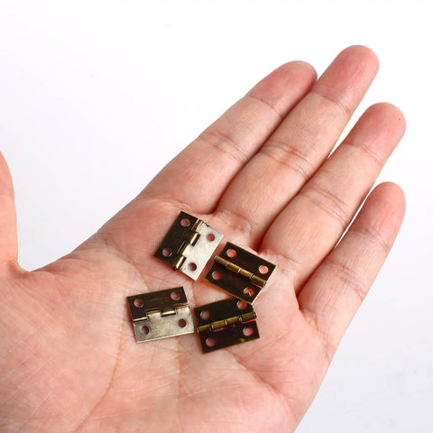 Fifty Piece Mini Bronze Butt Hinges With Two Hundred Matching Screws Top Shelf Gear For Diy Crafts Jewelry Boxes Wooden Cases And Dollhouse Builds Heavy Duty Hardware That Truly Holds Tight held in a hand.