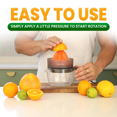 Primtronic Electric Citrus Juicer With Large 24 Oz Capacity And Seed Filter Auto Reverse Function Compact Design For Oranges Lemons Limes BPA Free Black Orange in use with fresh citrus.