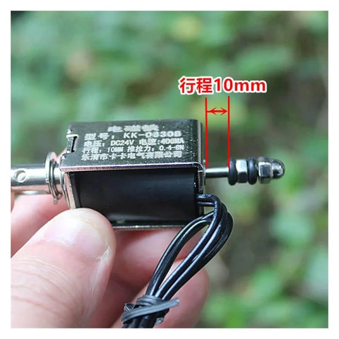 Close-up of 24V Linear Push Pull Solenoid Electromagnet Open Frame With Spring Plunger 10mm Stroke, hand-held with wiring visible.