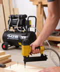 Person using nail gun connected to 6.4 Gallon Ultra Quiet Air Compressor With Steel Tank And Wheels Oil Free 70 Decibels 110V