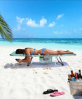 Woman relaxing on Reclining Beach Lounge Chair With Flat Lay Sunbathing Position, Folding Camping Cot With Backpack Straps, Portable Outdoor Chair For Beach Or Picnic, Lawn, Side Pockets For Drinks And Gear on sandy beach with ocean view.