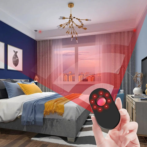 Hand holding Camera Detector With Led Infrared Scanning Technology for detecting hidden cameras, red light visible in a bedroom.