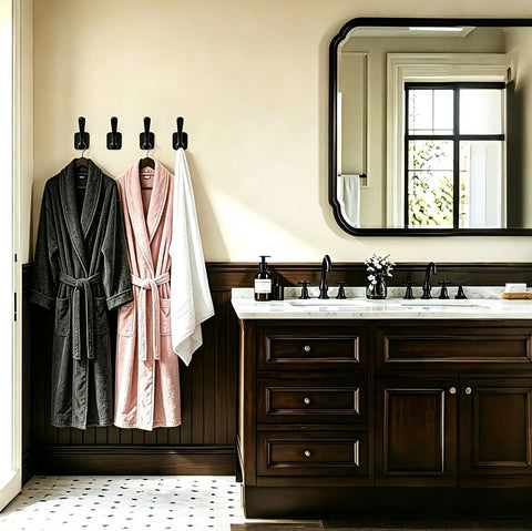 Top Shelf Matte Black Wall Coat Hooks Four Pack holding bathrobes in a stylish bathroom setting with a modern sink.