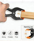 Hand using 12 Pack Heavy Duty 4.5 Inch Spring Clamps With Grip Jaw Pads For Photography Studio Backdrops And Carpentry Projects, durable