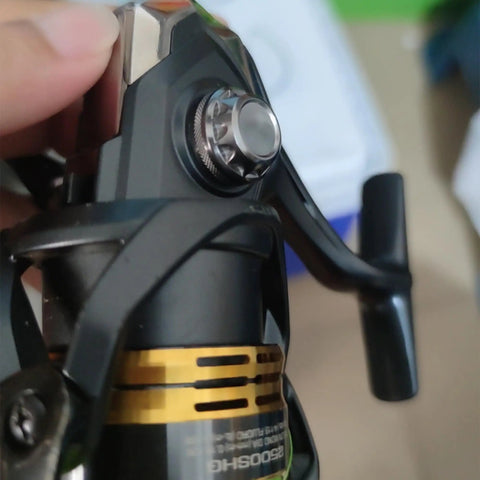 Close-up of an installed aluminum alloy fishing reel cap replacement for spinning reels showing the precision screw nut accessory kit.