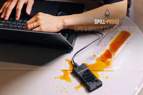 TUF Gaming A2 USB C 3.2 Gen 2x2 Portable SSD Enclosure handles spill next to laptop, showing MIL STD 810H drop resistance.