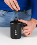 Man using Tutto Crema Milk Frother Black Barista Grade, 1L Capacity, with handle, double fine mesh insert in kitchen.