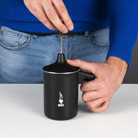 Man using Tutto Crema Milk Frother Black Barista Grade, 1L Capacity, with handle, double fine mesh insert in kitchen.
