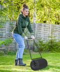 Woman using heavy duty lawn roller with adjustable weight system, 10 gallon capacity, fill with water or sand to dial in rolling pressure from 17.6 lbs to 100 lbs, great for seedbeds and sod, durable black powder coated steel frame