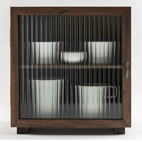 Wooden cabinet with fluted glass door showcasing white cups and bowls inside, metal handle, antique design