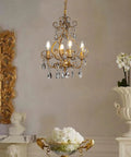 Four Light Crystal Chandelier in Antique Gold 14 Inch Diameter Dining Room Pendant Swag Light With Teardrop Beads Vintage Gothic Style Adjustable 76 Inch Chain E12 Bulb Compatible Bulbs Not Included hanging in an elegant room.