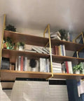 Heavy Duty Three Tier Floating Shelf Brackets Wrought Iron Ceiling And Wall Mount 11x43 Inch 110 Lbs Capacity Includes All Hardware mounted with books and plants.