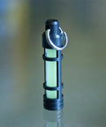 Embrite Glow Fob With Green Embrite Pellet, Aircraft-Grade Aluminum Keychain Accessory standing on reflective surface