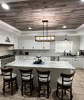 Modern kitchen featuring white cabinets, gray granite countertop, and wooden ceiling with stylish island seating.
