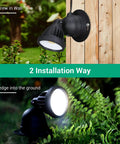 Outdoor Spotlight Kit 2 Pack Dusk To Dawn 120V 12W 4000K 1150LM IP65 LED mounted on wall and in-ground in garden setting.