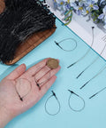 2000 Pack 5 Inch Black Plastic Hang Tag Loops Featuring Straight Up Secure Snap Lock Fasteners in hand with coin for size.