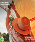 Person inside Lightweight Beach Shade Tent With Pre Attached Poles Large Sun Shelter For Sand And Sun showing rear vent and gear pockets