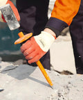 Worker using Beefy 12-Inch Flat Chisel With Bi-Material Hand Guard for demolishing concrete, wearing gloves, heat treated CRV steel.