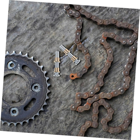 Rusty metal chain and gear with bolts on textured surface, viewed from above