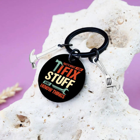 Keychain Gift For Men I Fix Stuff And I Know Things Ideal Dad Gift with black round keychain and mini tools on rock surface