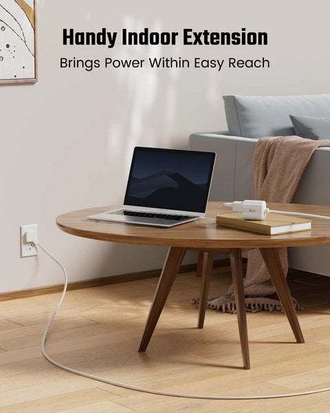 No More Juggling Plugs Ultra Slim 1.5 Ft Flat Extension Cord With Three Grounded Outlets used under a wooden coffee table.