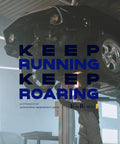 Car on lift with "Keep Running Keep Roaring" text overlay in automotive workshop setting.