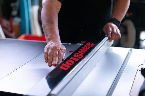 Close-up of hand adjusting Advanced T Glide Rip Fence Rock Solid Design With Dovetail Slots Compatible With Industrial Cabinet Saw.