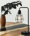 Two Pack Industrial Table Lamps With Dual USB Ports And AC Outlet on wooden table, black metal cage shade with vintage bulb