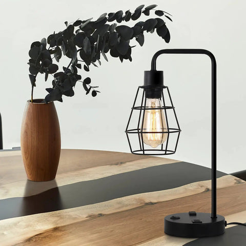 Two Pack Industrial Table Lamps With Dual USB Ports And AC Outlet on wooden table, black metal cage shade with vintage bulb
