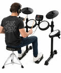 Person playing FED150 Electronic Drum Set For Beginners with Quiet Mesh Pads, four-zone snare, headphones, and drum throne