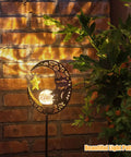 Lit Moonlit Solar Lantern for Outdoor Decor casting warm LED glow against brick wall with crackle glass globe, bronze finish.
