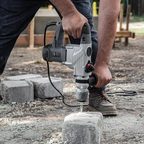 Electric SDS-Plus Rotary Demolition Hammer 1180W with 1-1/4 inch bit in use on concrete block outdoors