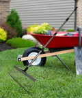 Workhorse Heavy Duty Lawn Rake With Telescoping Handle resting against a wheelbarrow in a garden setting