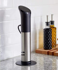 Precision Cooker Base Stand And Anchor Black Small Accessory holds cooker upright on kitchen counter with spices in background.